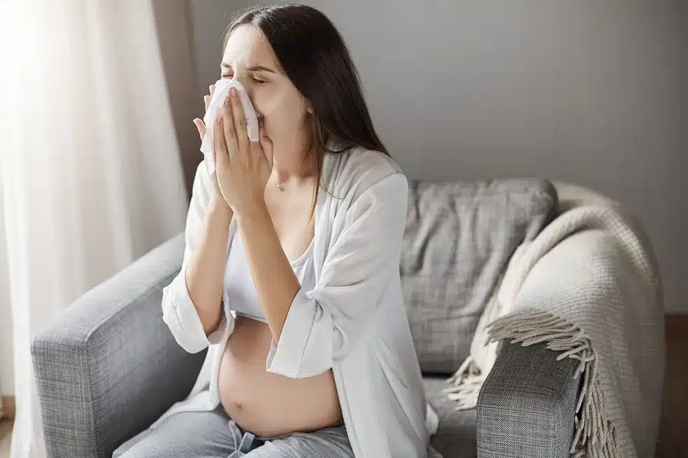 jovem gravida com gripe tossir e usar um lenco de papel