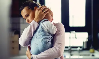 jovem mae preocupada confortando seu bebe chorando em casa