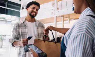 saleswoman handing bag to smiling customer at the store